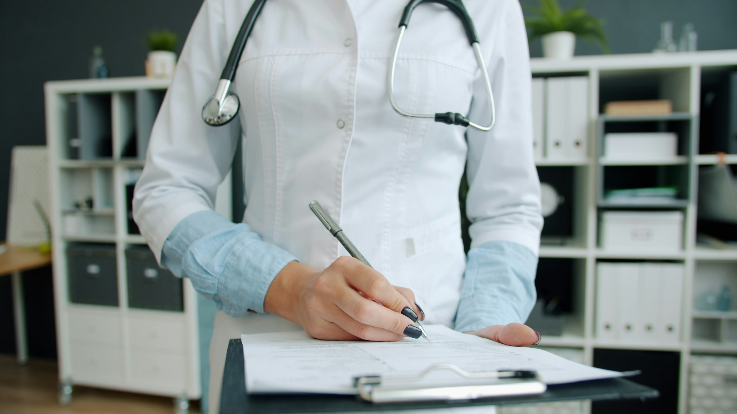 Close-up shot of hand of doctor writing in patient's medical records ticking symptoms working in hospital office. Medicine, paperwork and profession concept. Photo by Vitaly Gariev on Unsplash